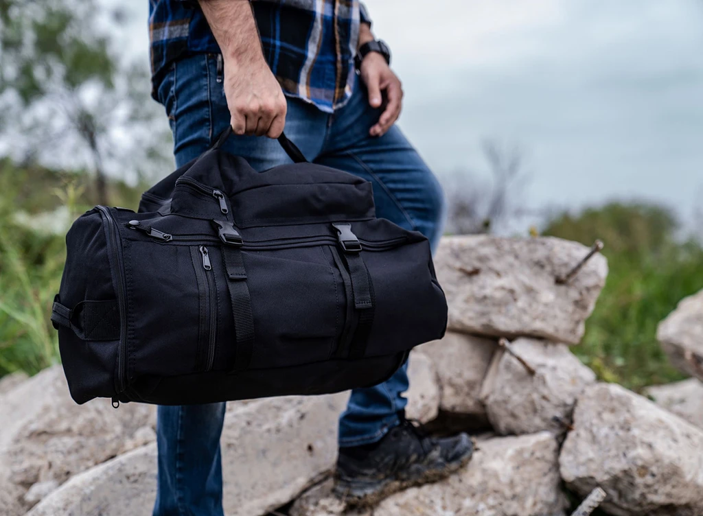 GTFO Top Load Duffel Backpack in black carried as a duffel.