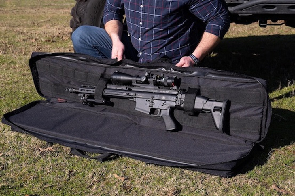 Black Single Rifle Case being held opened with firearm secured inside.