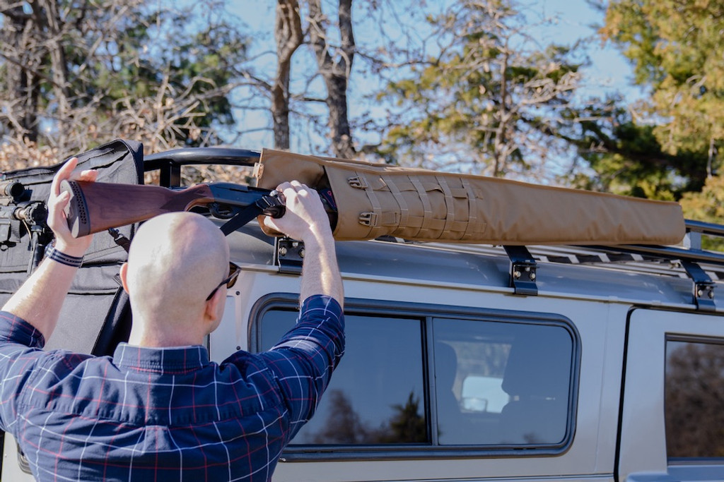 Shotgun being removed from coyote brown Shotgun Scabbard on top of grey sports utility vehicle.