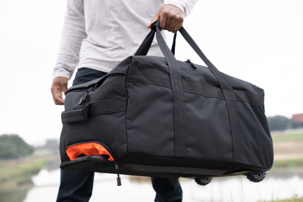 Mini Buffalo Rolling Duffel in Black carried as duffel showing the side and top with retractable handle inside.