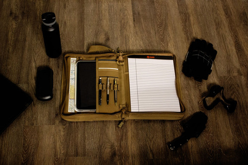 Secret Squirrel Tactical Padfolio in Coyote Brown open on table with tablet, pens, and iPad® inside.