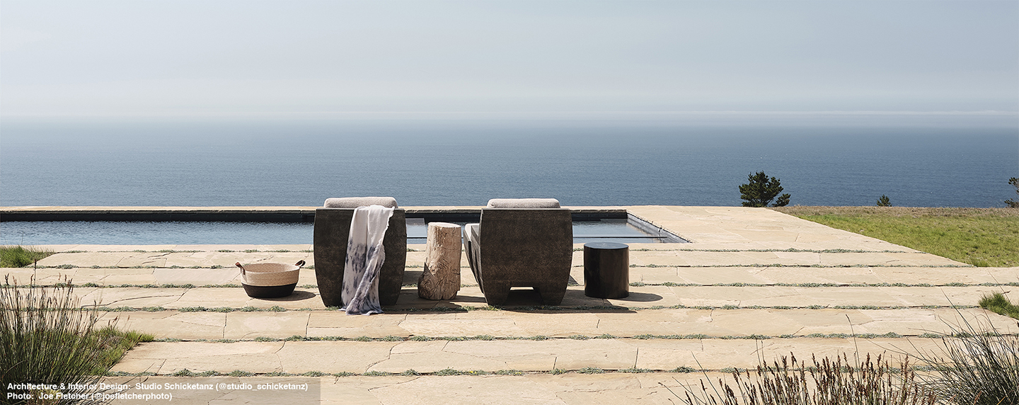 2 Zaragoza Arm Chairs by a  rectangular pool and view of the ocean in horizon.