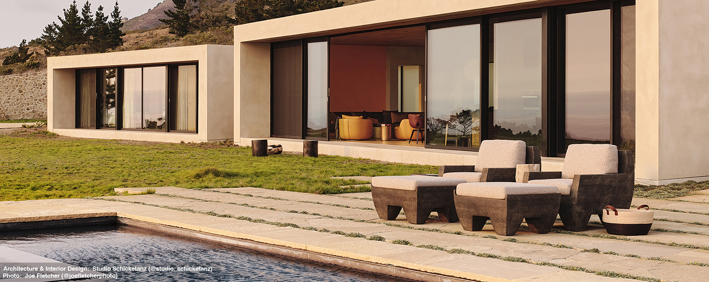 Zaragoza Arm Chairs and ottomans with cushions  by a pool with a modern home in background