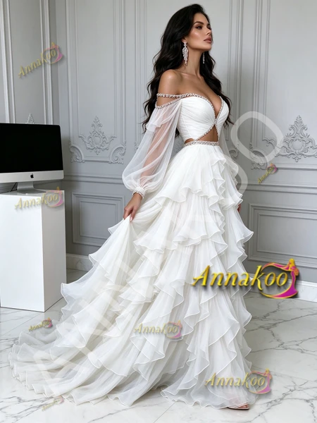 Side profile highlighting the airy multi-layered tulle ruffles and sheer long sleeves of the white prom gown.