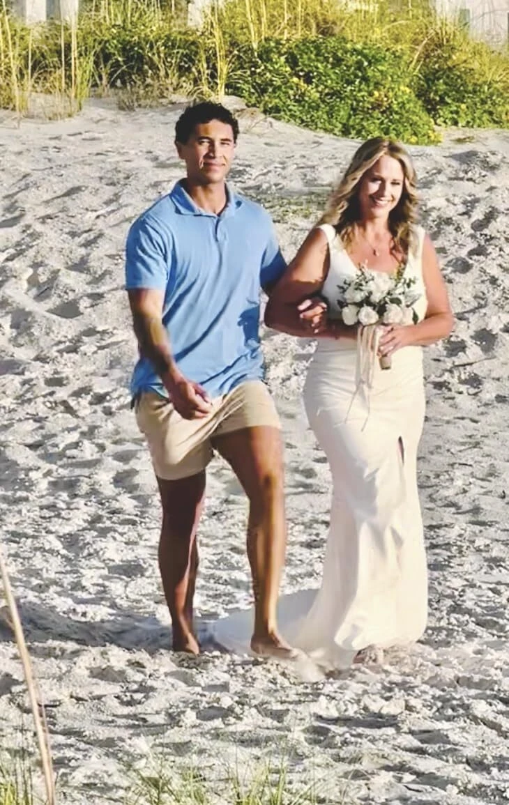 Bride and groom walking through dunes in a white high slit mermaid wedding dress