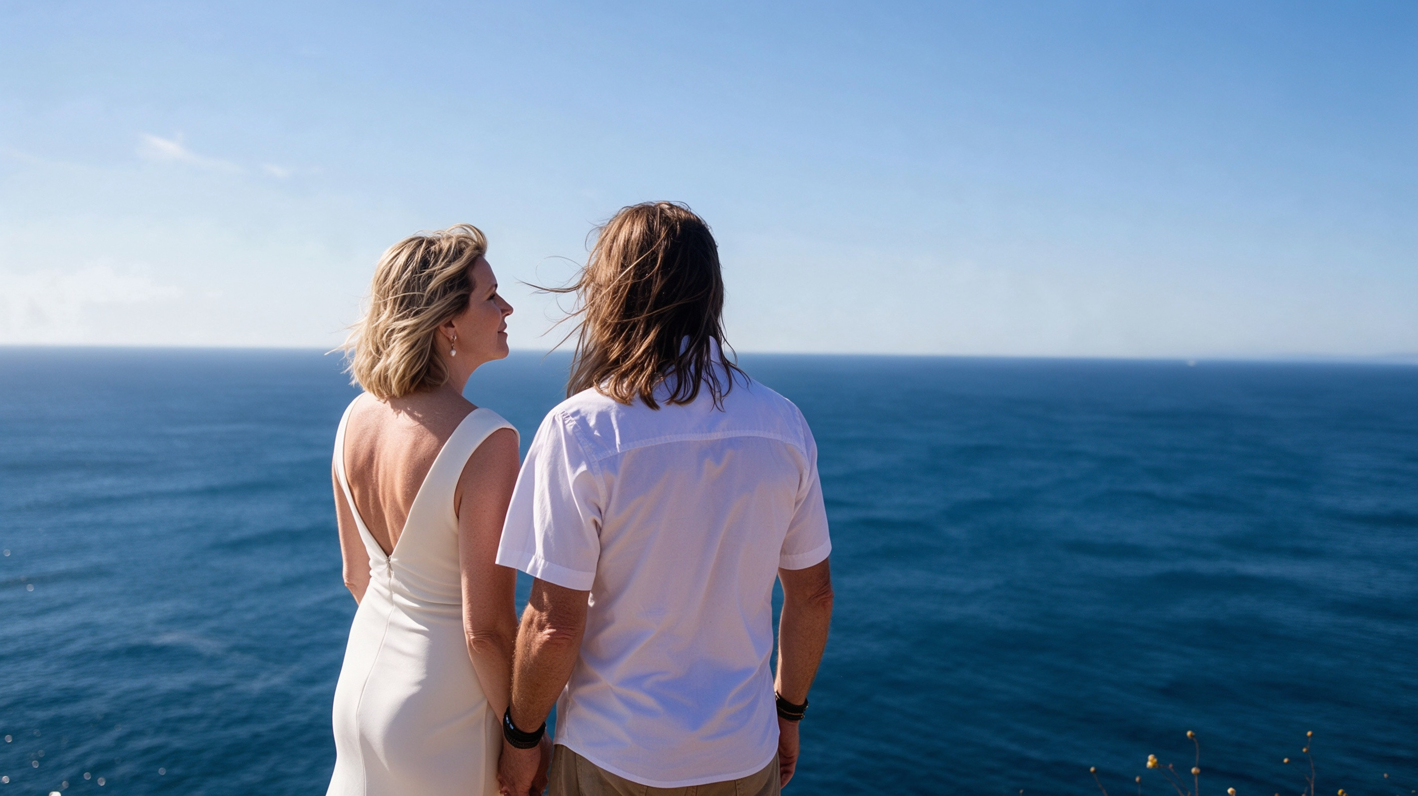 Bride and groom looking toward the Atlantic with wedding dress train blowing in the wind