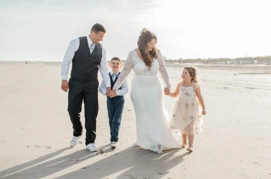 Big family walking hand in hand along beach shoreline at wedding
