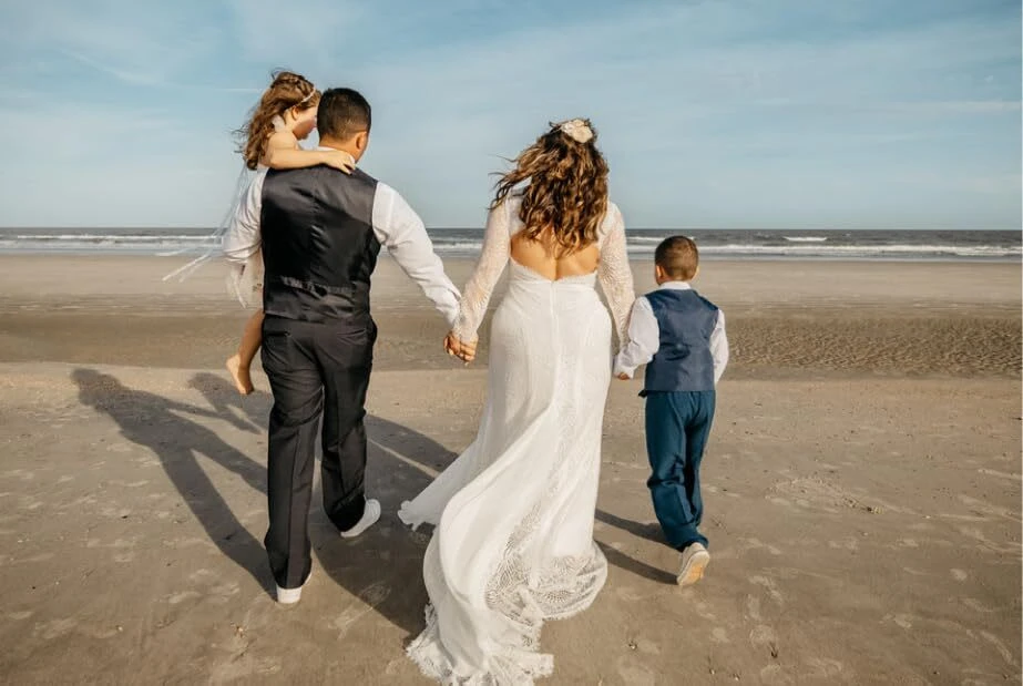 Family back view walking toward sea at beach wedding