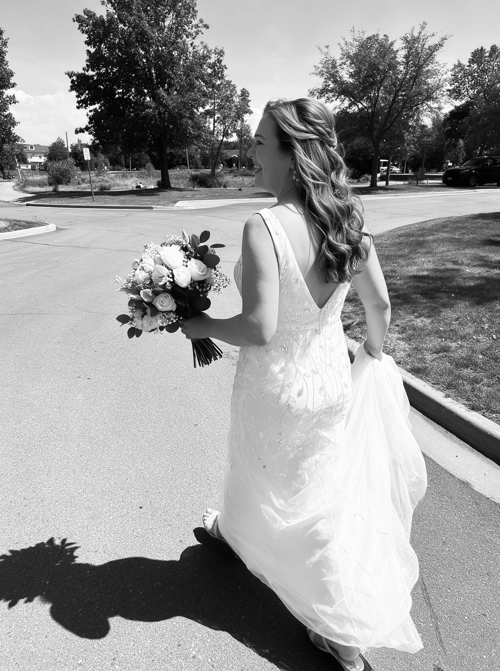 Black and white back view of the bride walking with her wedding bouquet