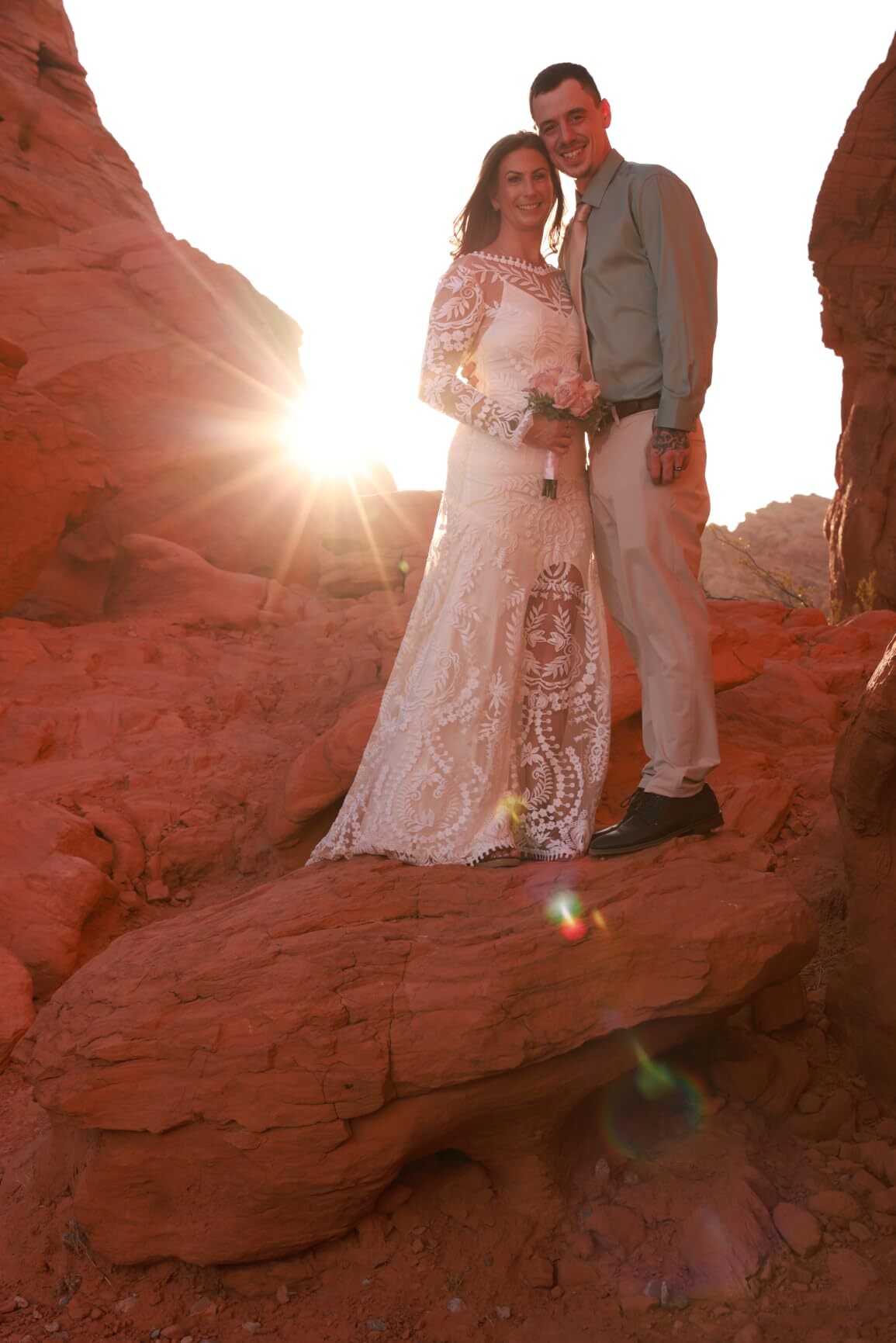 Bride wearing boho long sleeve lace wedding dress with groom at golden hour