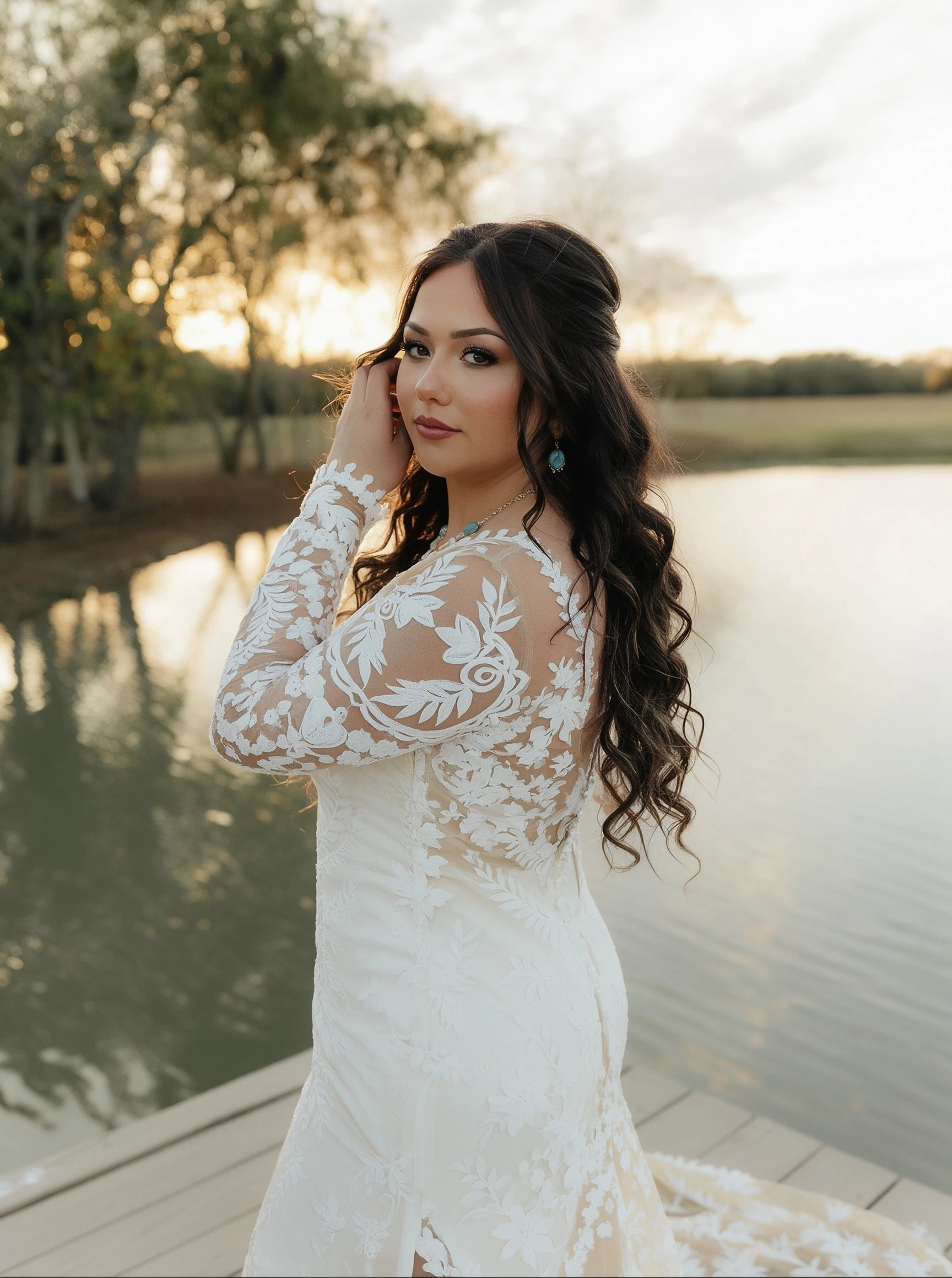 Bride in long sleeve lace wedding dress posing on wooden lake dock