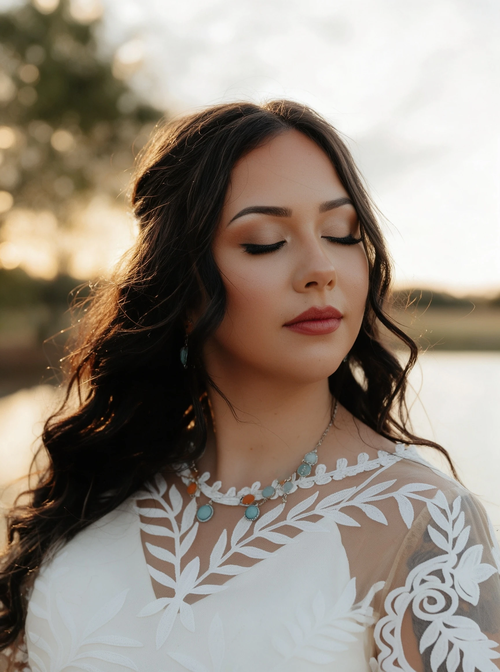 Bride wearing botanical lace wedding dress by lake during golden hour