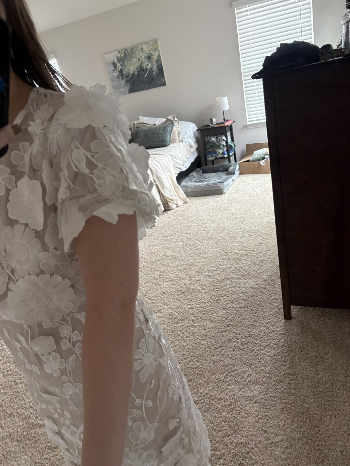 Close up of the three dimensional floral lace appliqu&eacute;s on a white dress