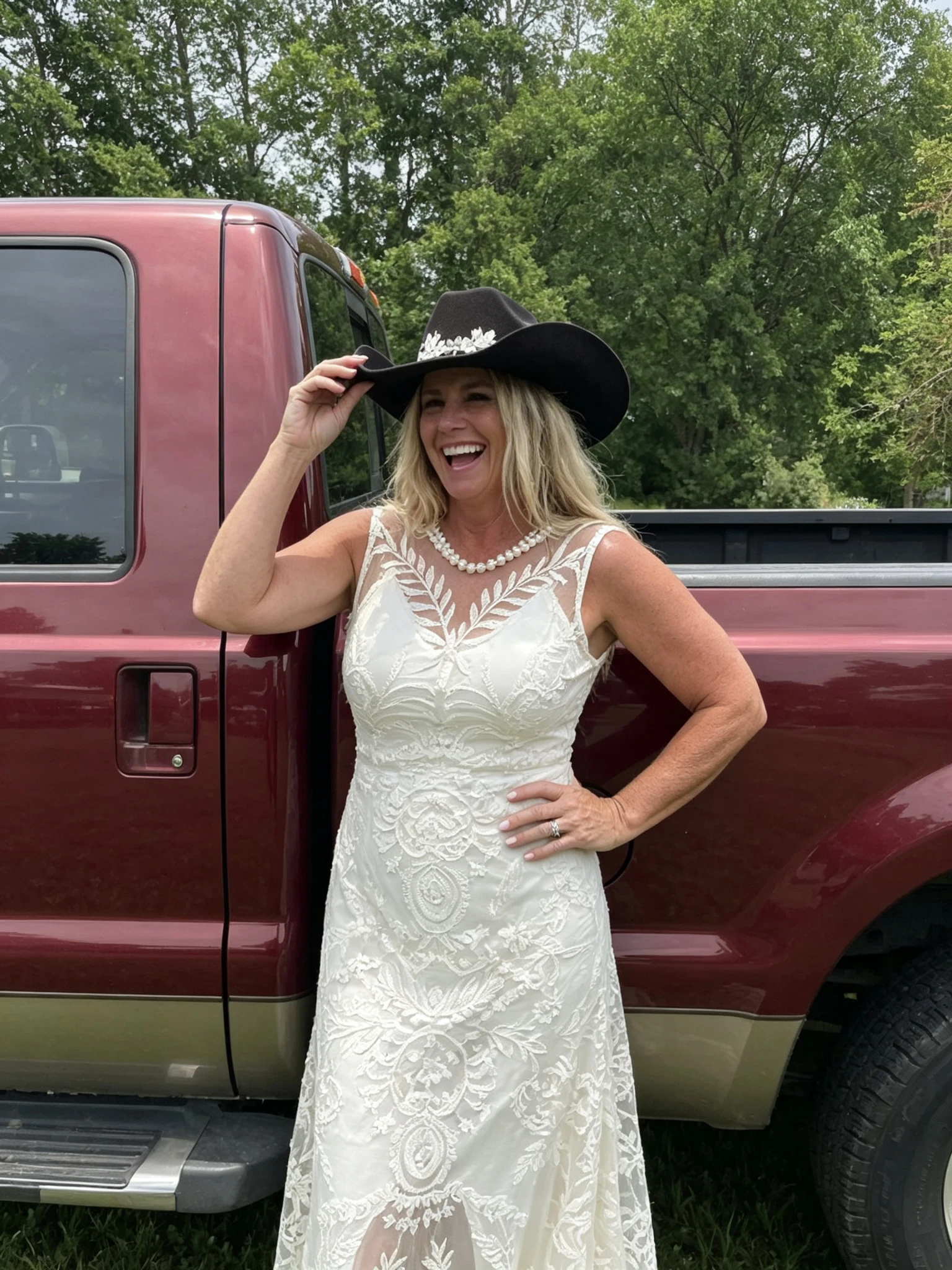 Bride wearing a country lace wedding dress beside a vintage red pickup truck