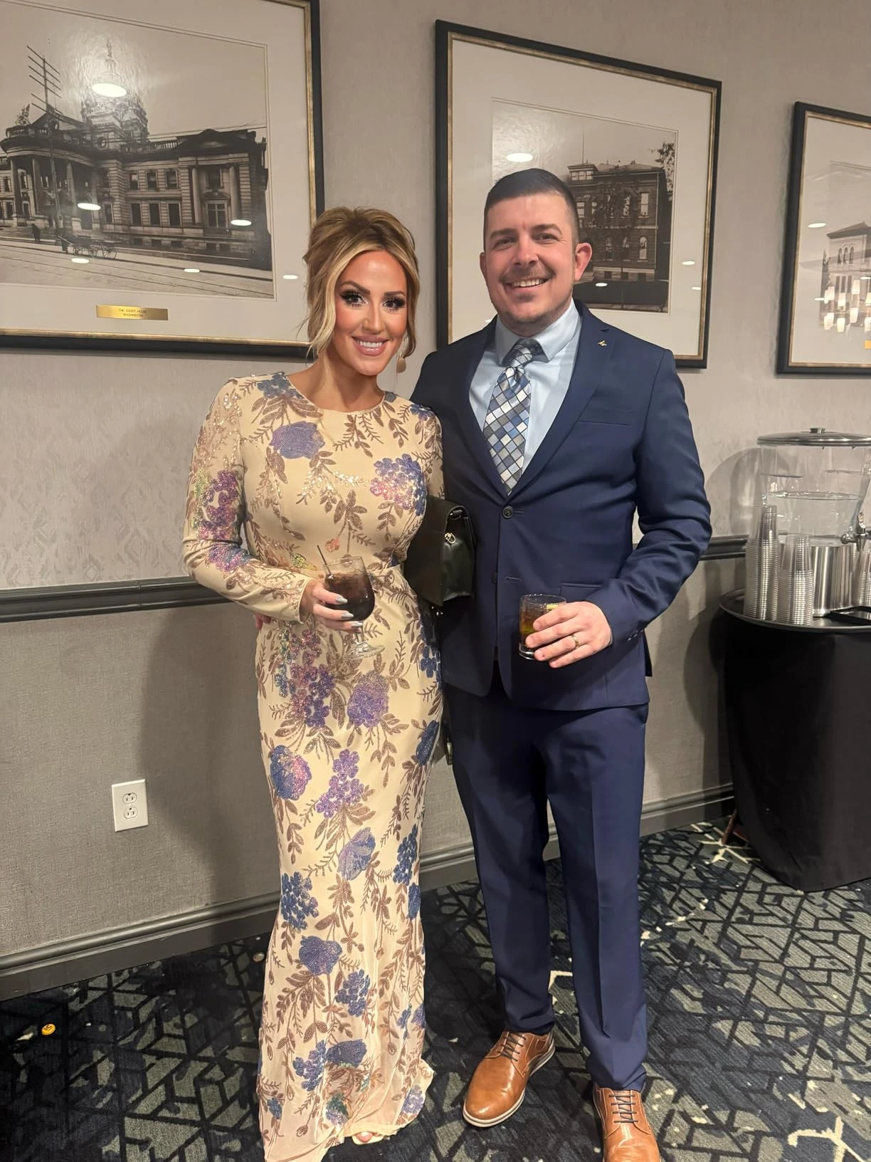 Couple posing together at a formal gala while woman wears a floral sequin gown