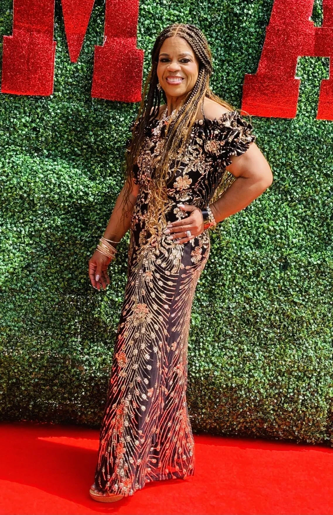 Curvy woman wearing sequin evening gown at green wall