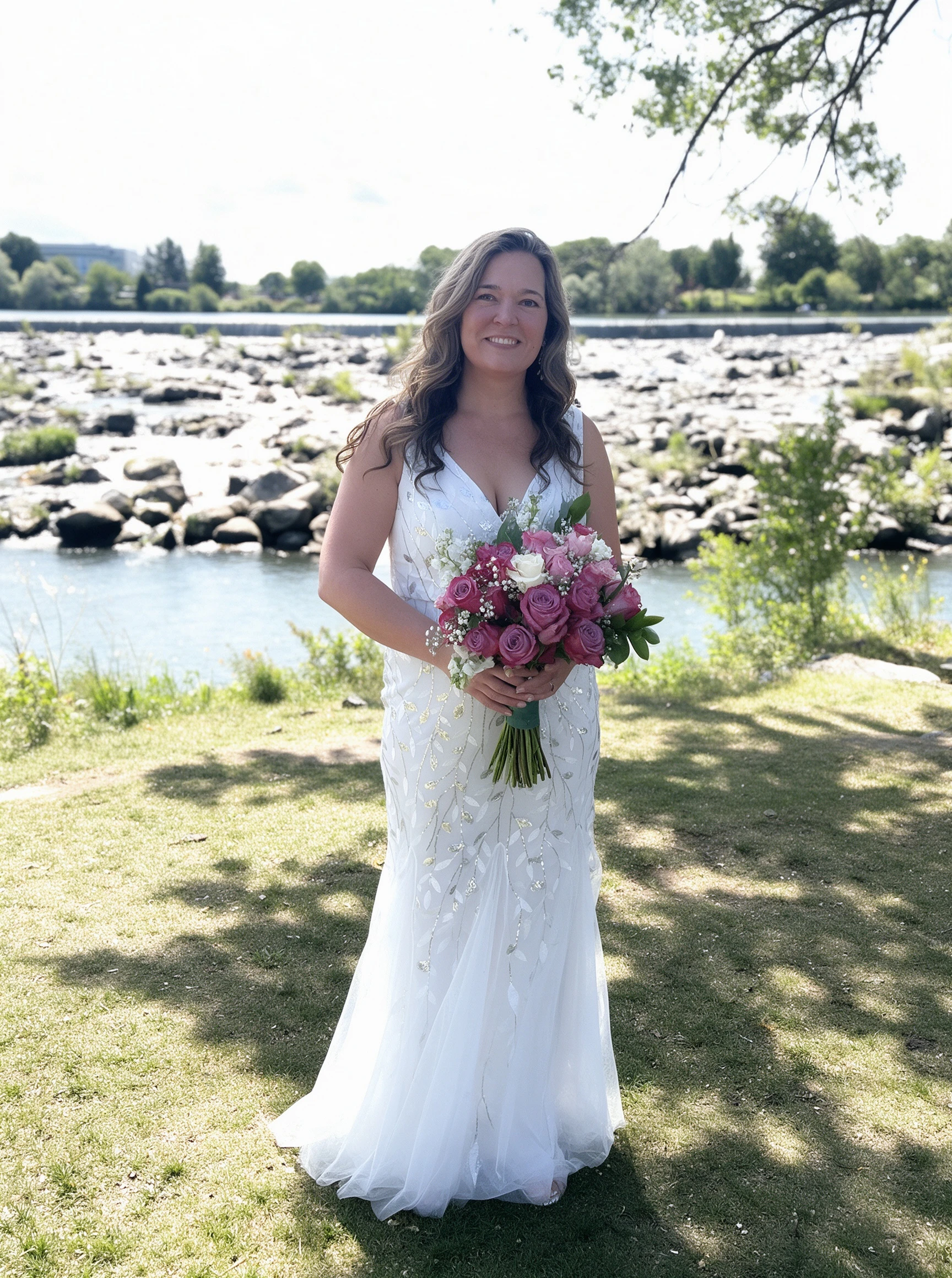 Full-length portrait of the bride in a silver leaf wedding dress on the riverside lawn