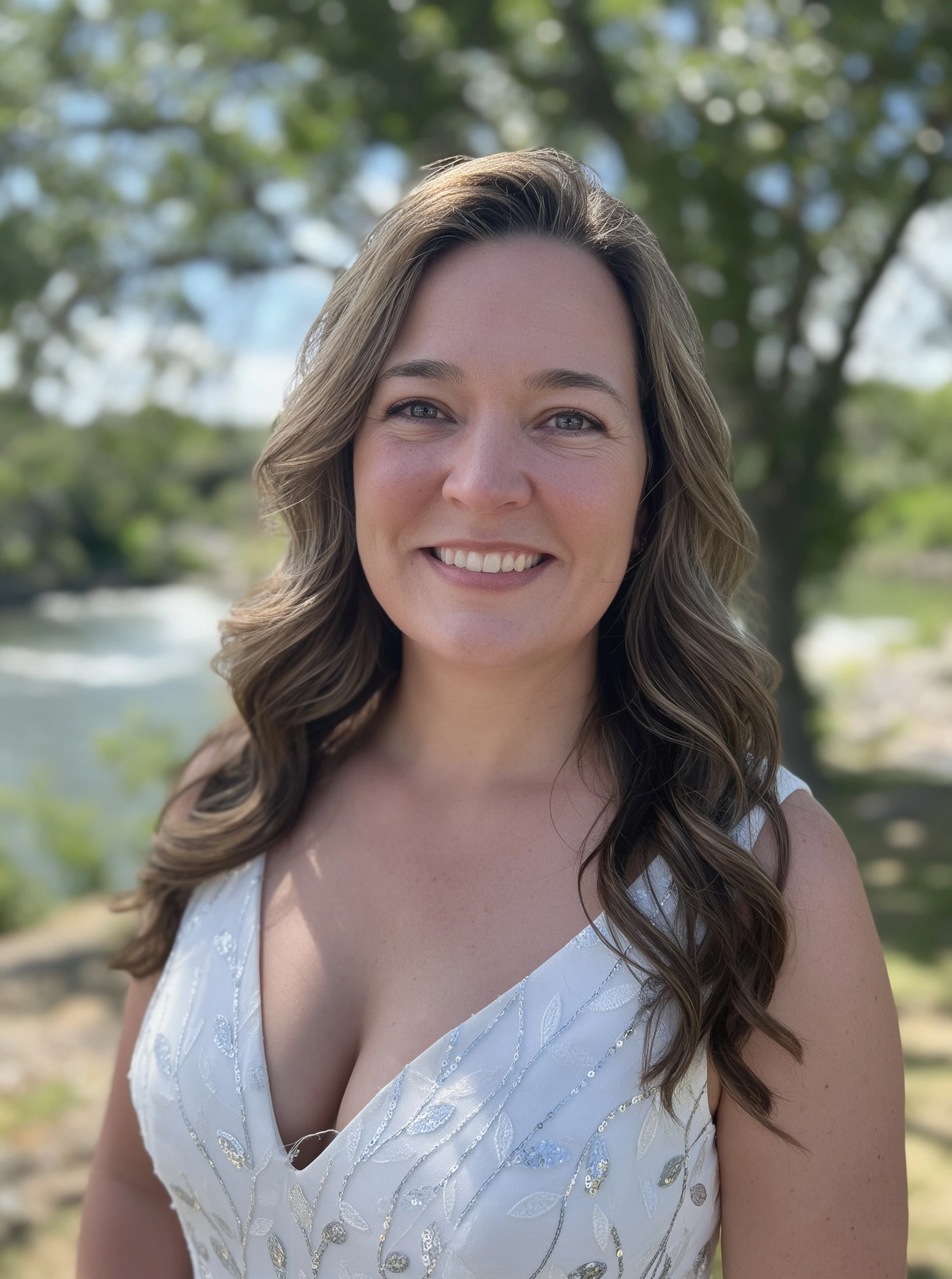 Half-body portrait of the bride smiling by the river in her beaded bridal gown