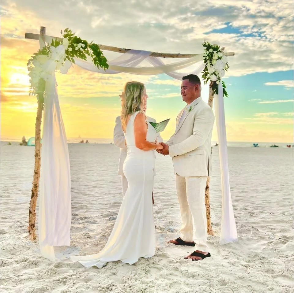 Bride and groom holding hands during sunset beach wedding vows