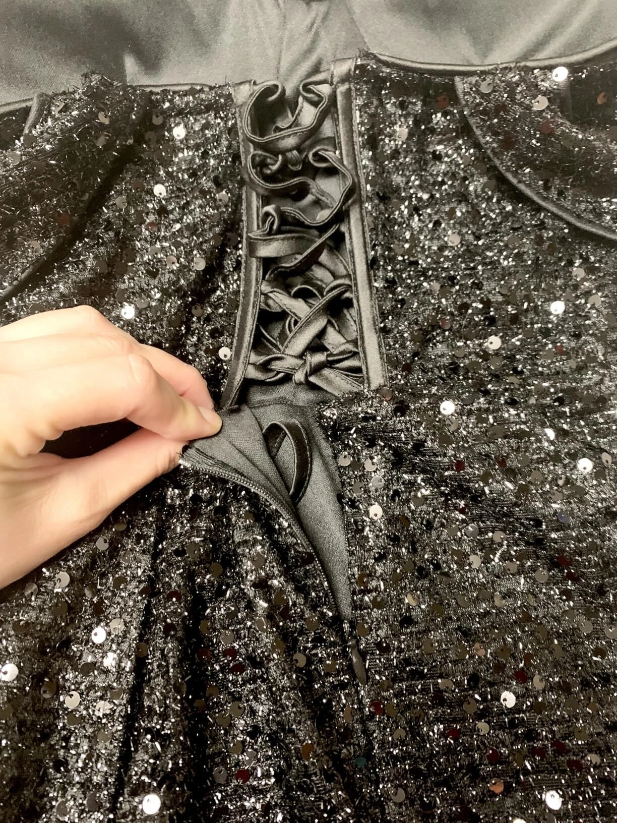 Close-up of hands adjusting the ribbon lace-up back on a formal prom dress