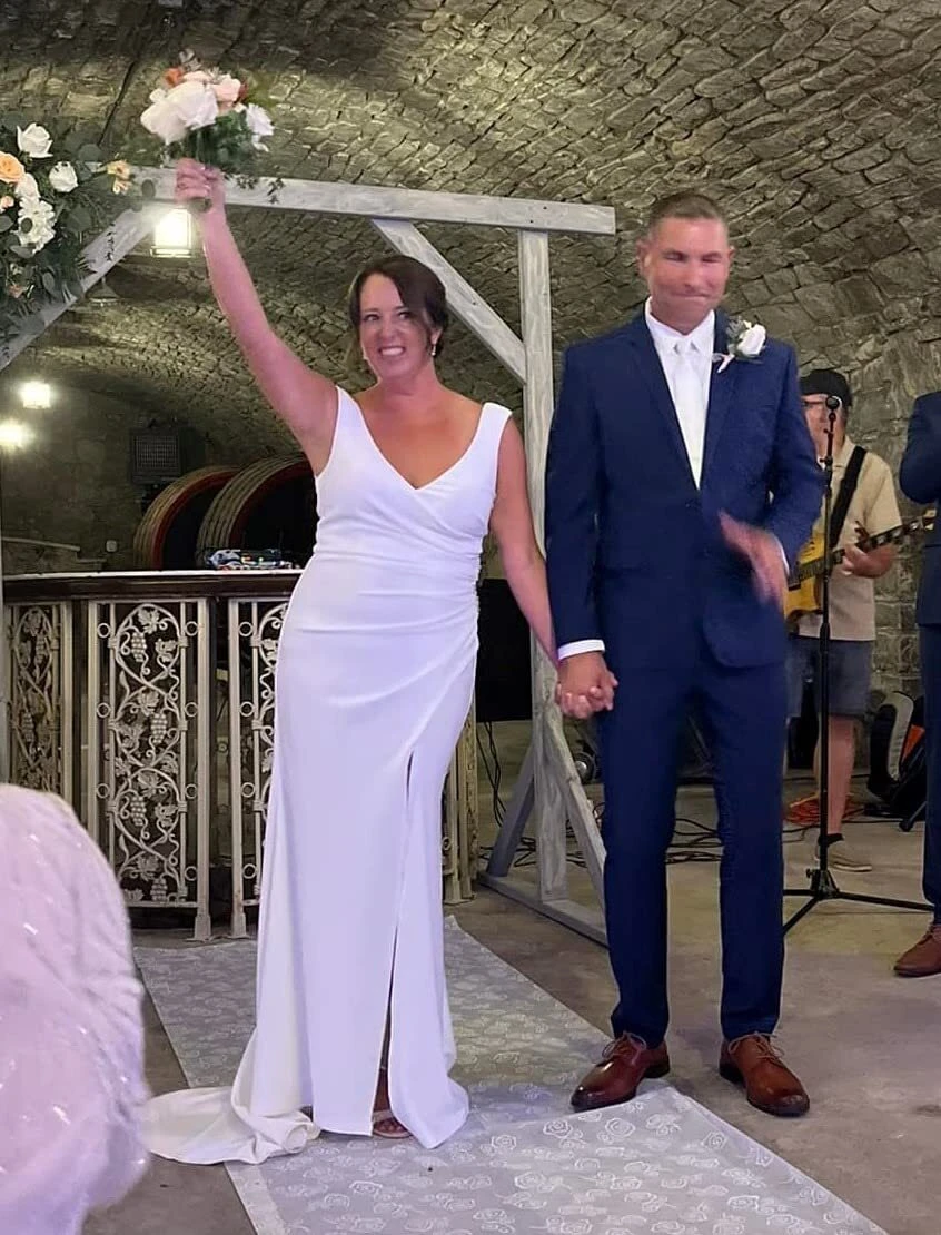 Newly married bride holding her bouquet high in a white crepe wedding gown