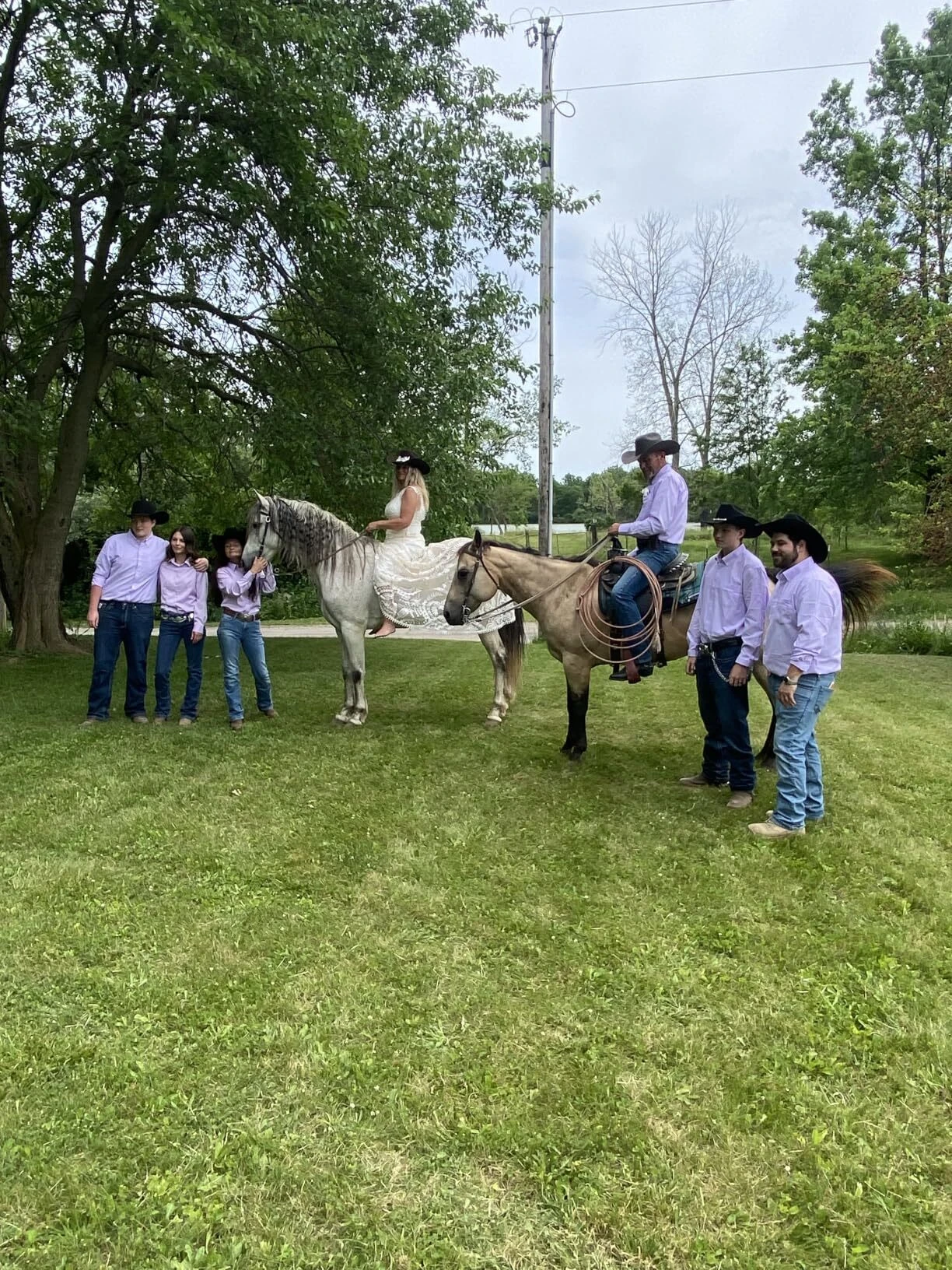 Bride in a lace wedding dress with a western wedding party and horses