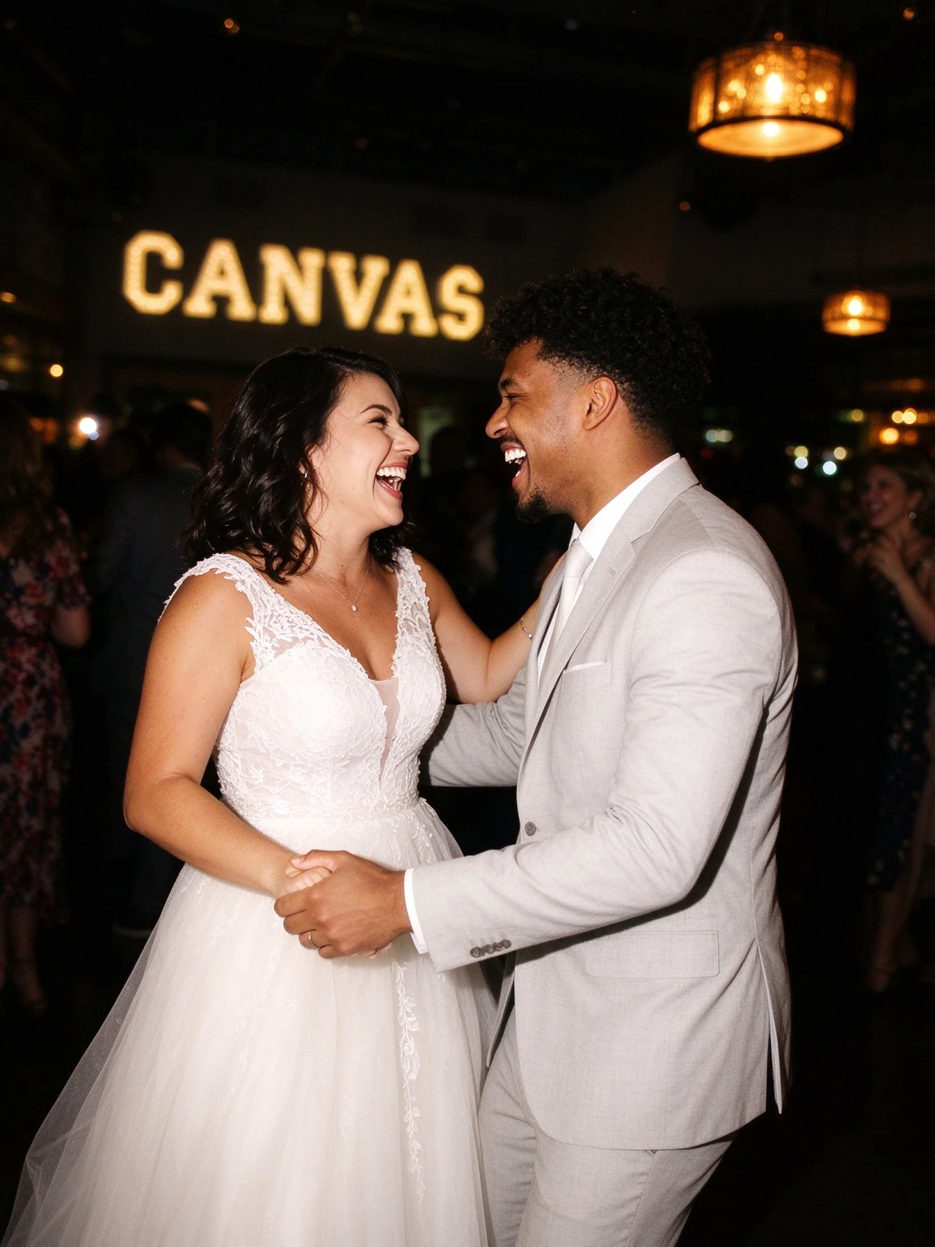Bride laughing with her husband while wearing a beaded waist lace wedding dress
