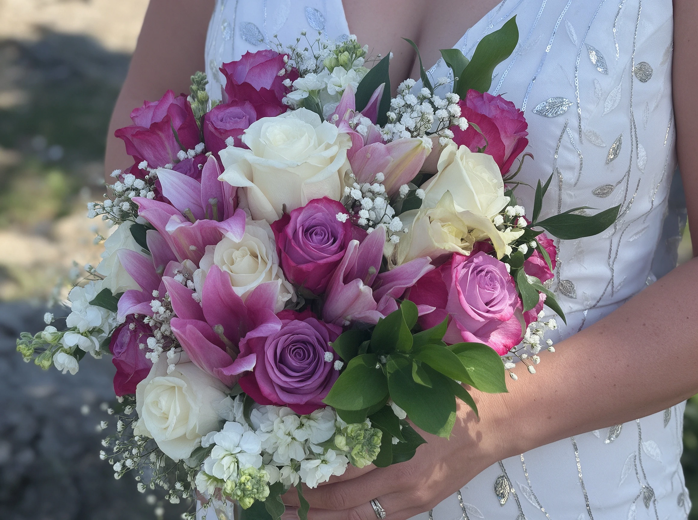 Close-up of the pink and white bridal bouquet resting on the sequin wedding gown