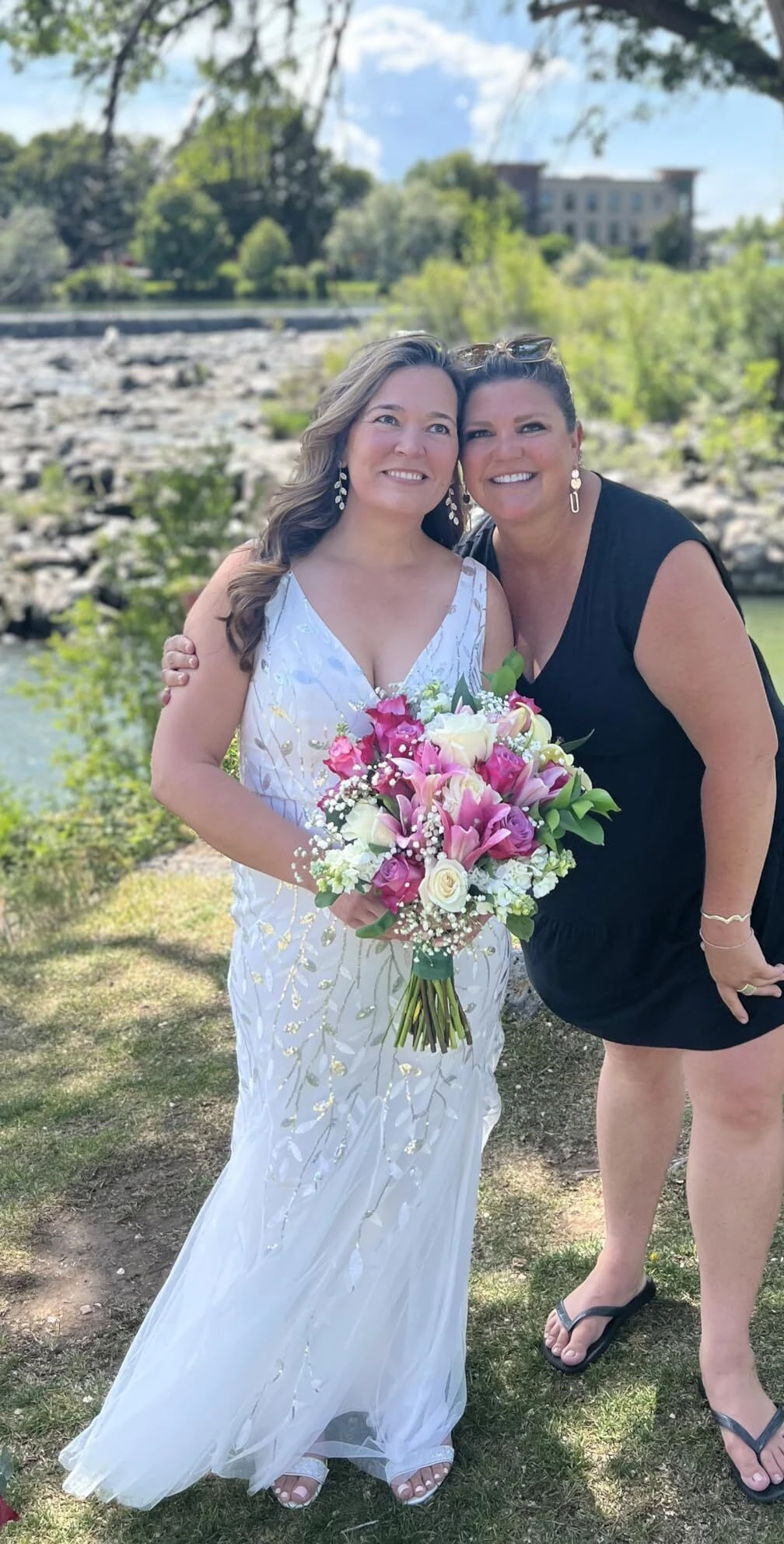 Bride and best friend posing by the river at a summer wedding in Idaho Falls