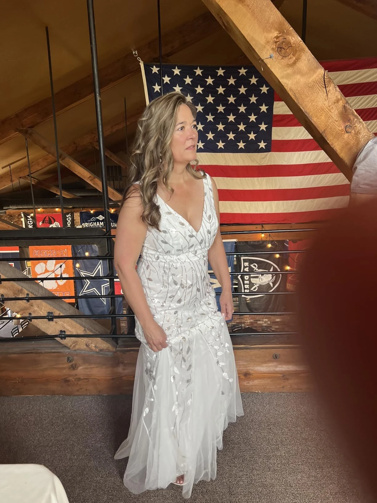 Bride lifting the tulle train of her wedding gown inside the barn reception