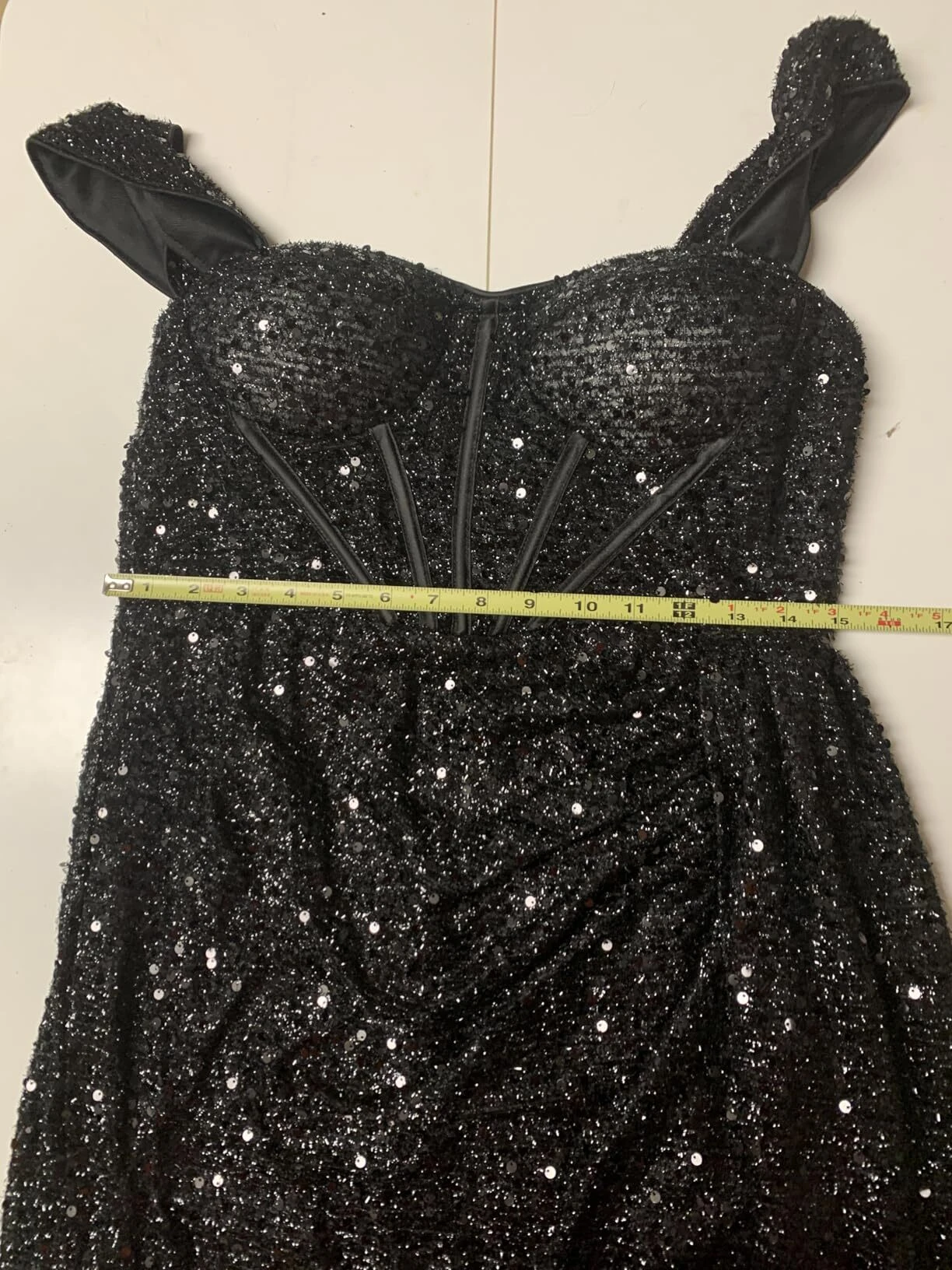 Measuring the waist area of a black sequin corset prom dress