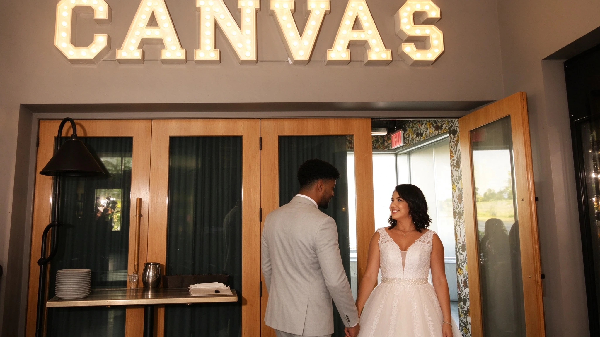 Bride wearing a lace gown with a beaded waist at the Canvas venue entrance