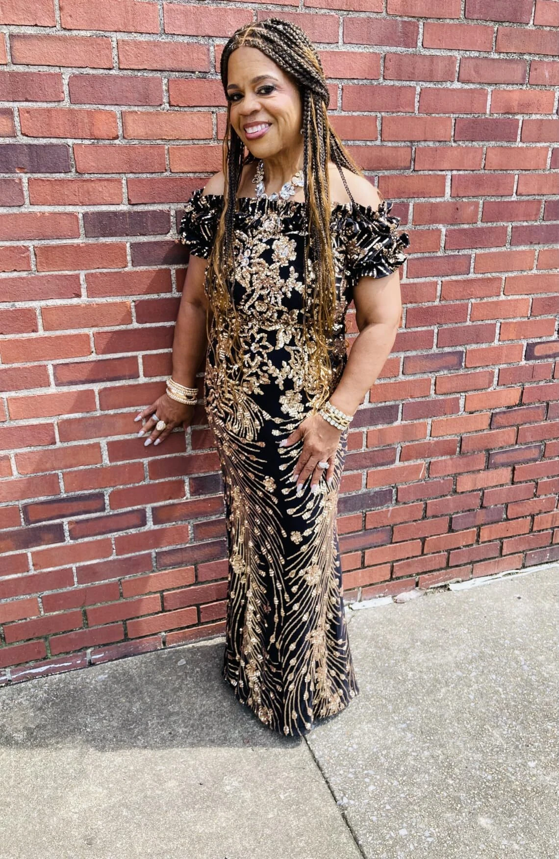 Black and gold sequin mermaid gown against rustic red brick wall