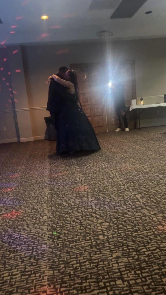 Bride and groom having their first dance while the navy blue gown catches the spotlight