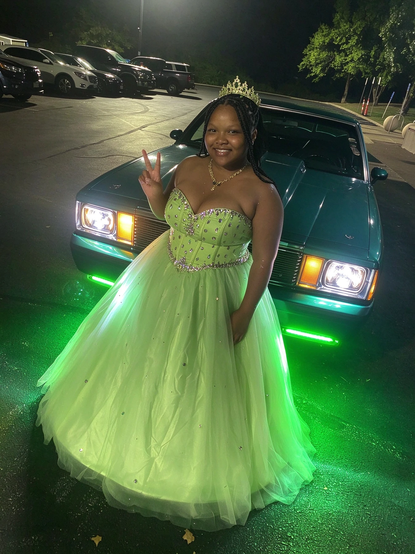 Lime green ball gown in a playful peace sign pose during formal night photographs