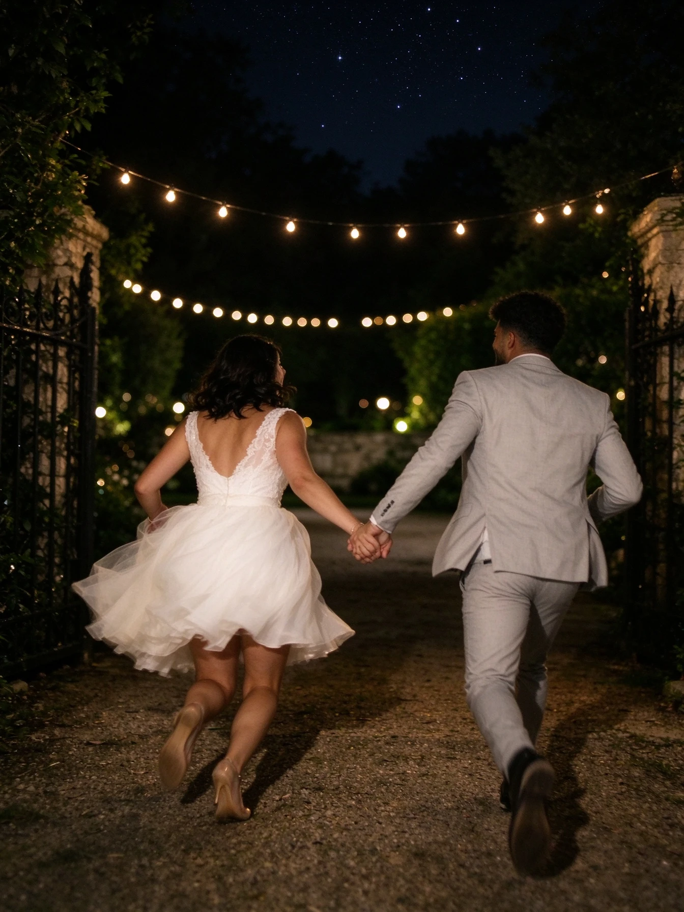 Bride running beneath string lights in a soft flowing tulle wedding gown