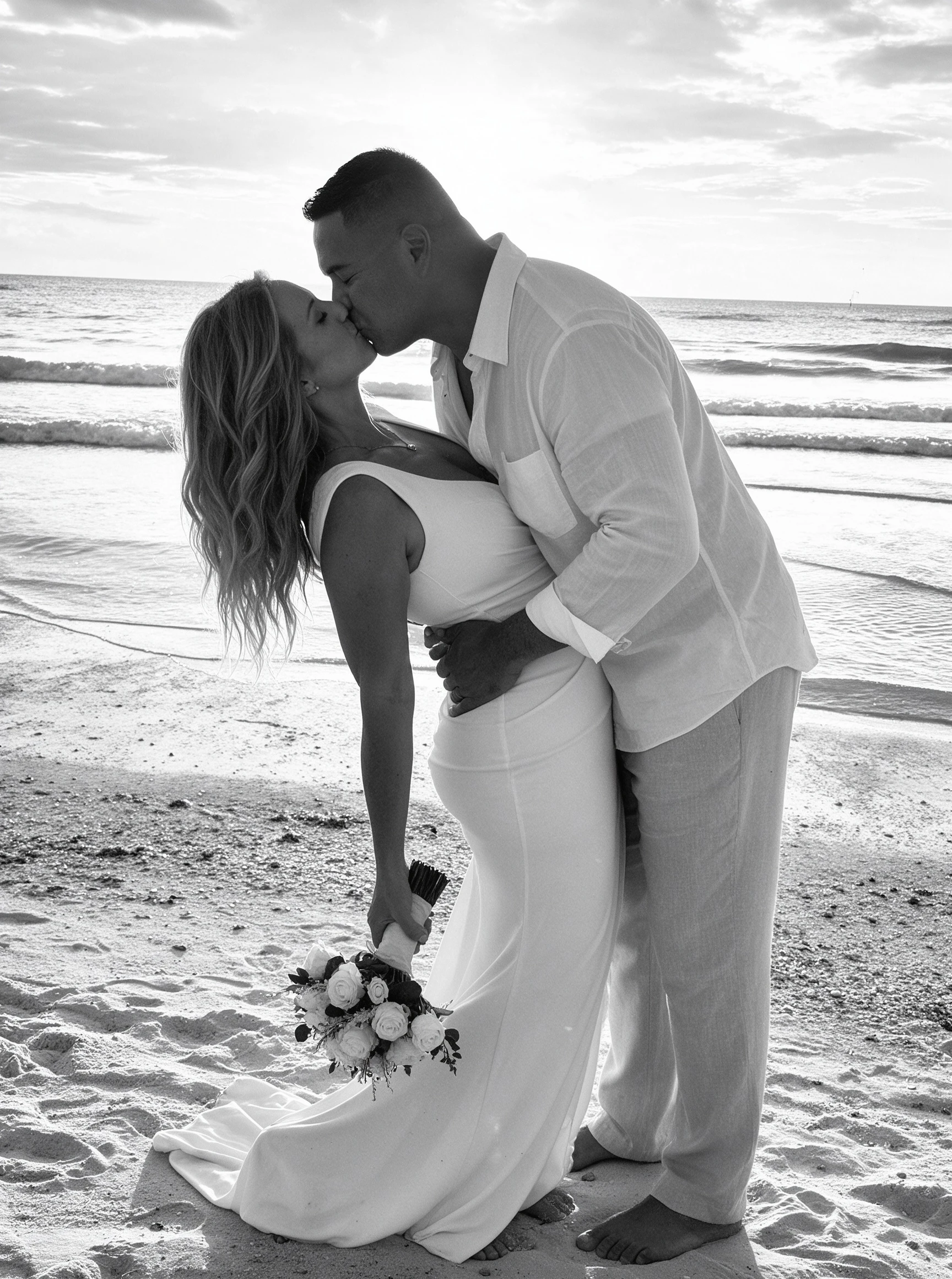 Bride and groom kissing at the shoreline during a sunset beach wedding