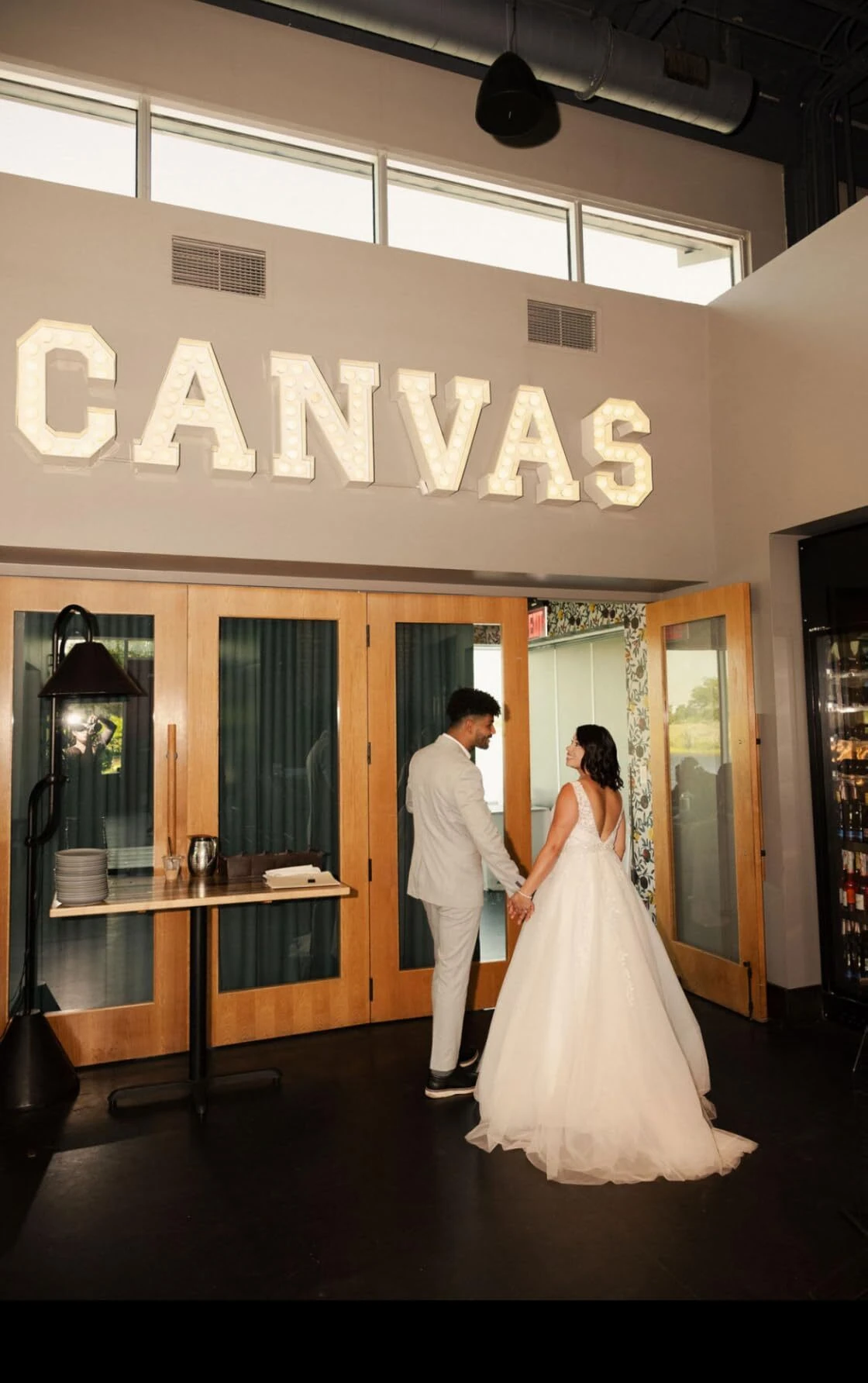 Bride standing at the Canvas doorway wearing an open-back lace wedding gown