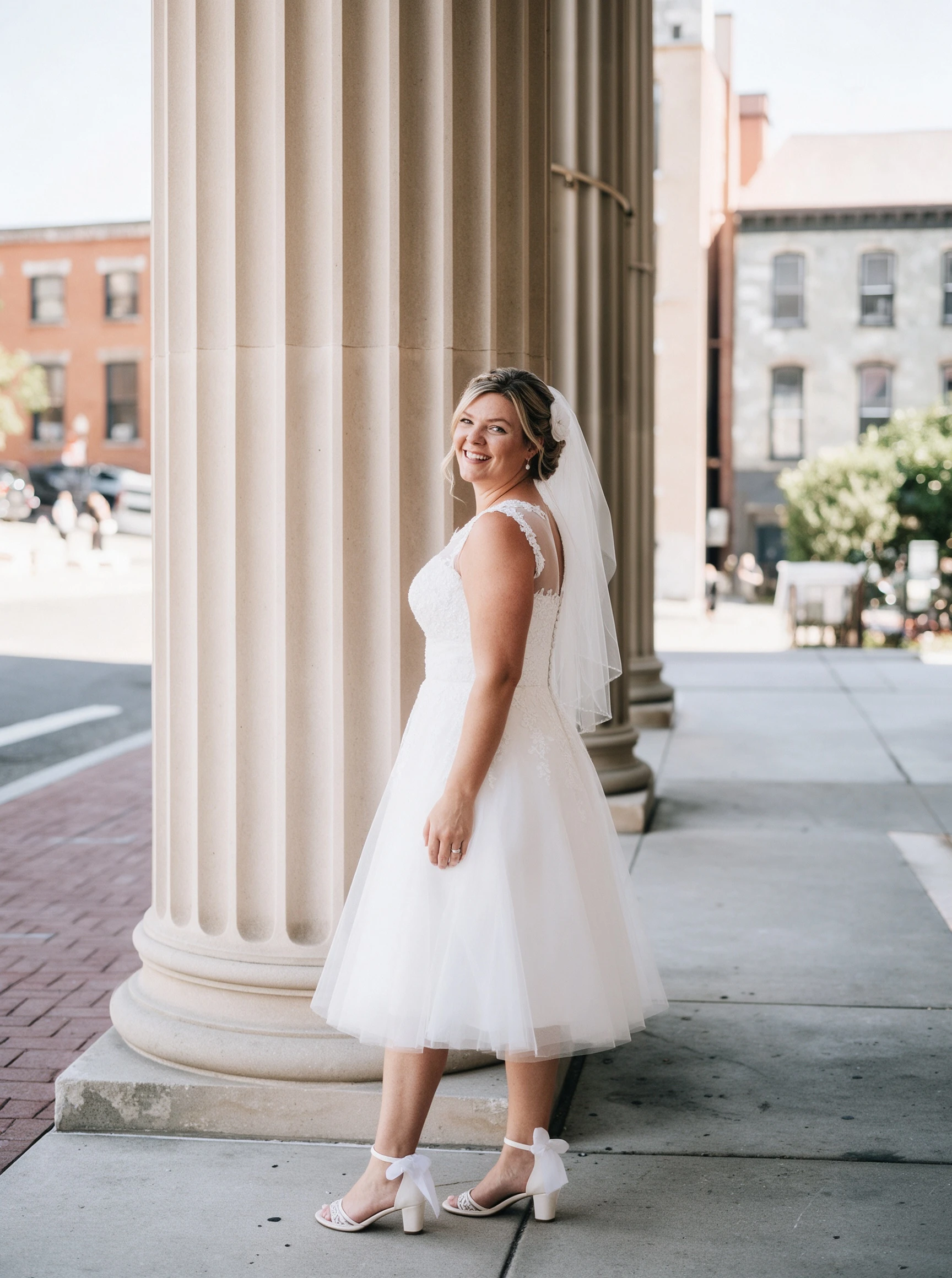 Standing beside stone columns in my short lace wedding dress
