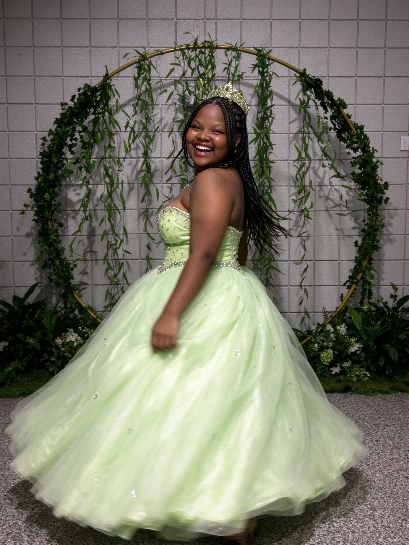 Strapless sweetheart lime green ball gown photographed beside a greenery arch