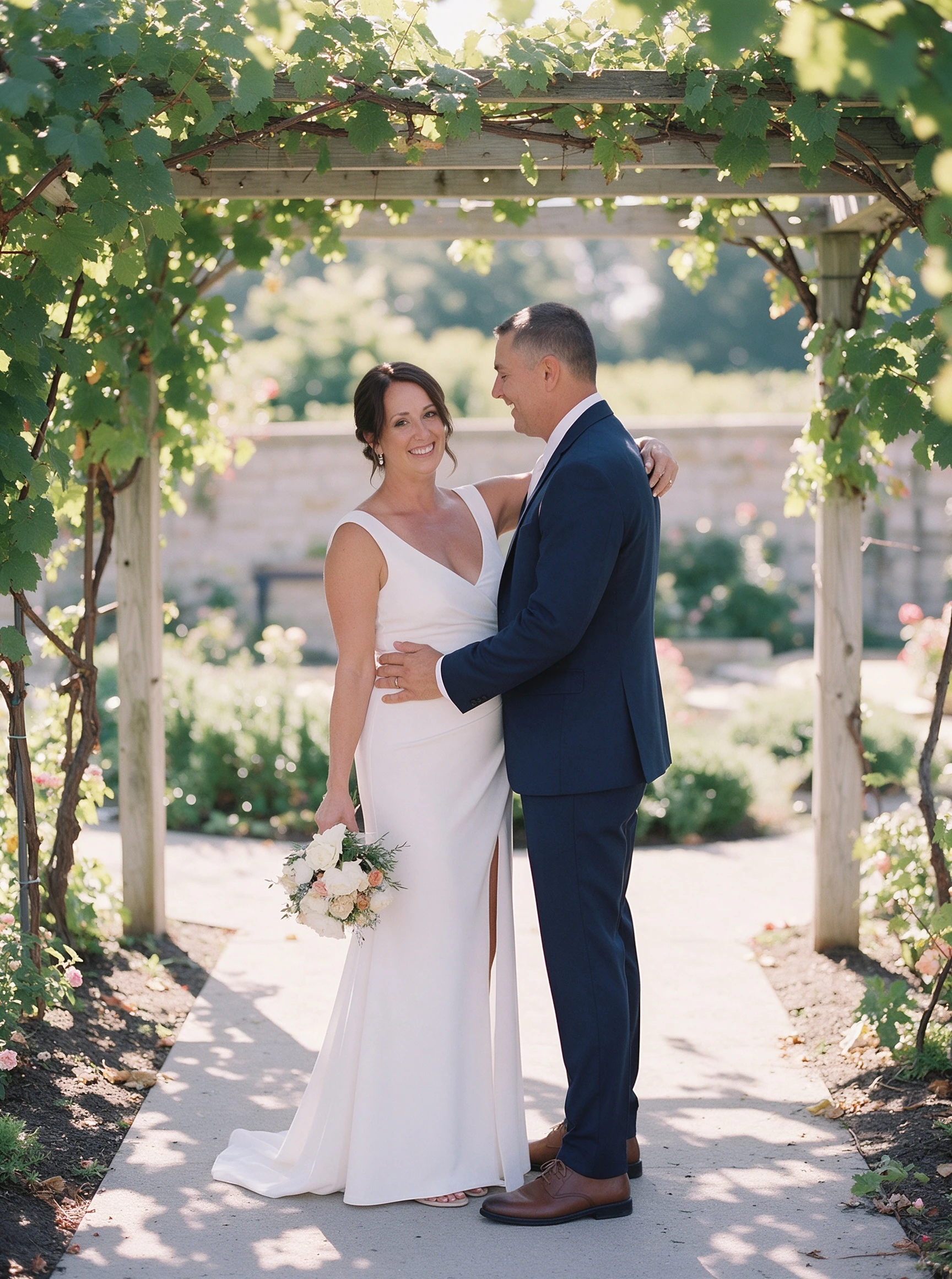 Bride standing beneath a grapevine pergola in a white crepe wedding gown