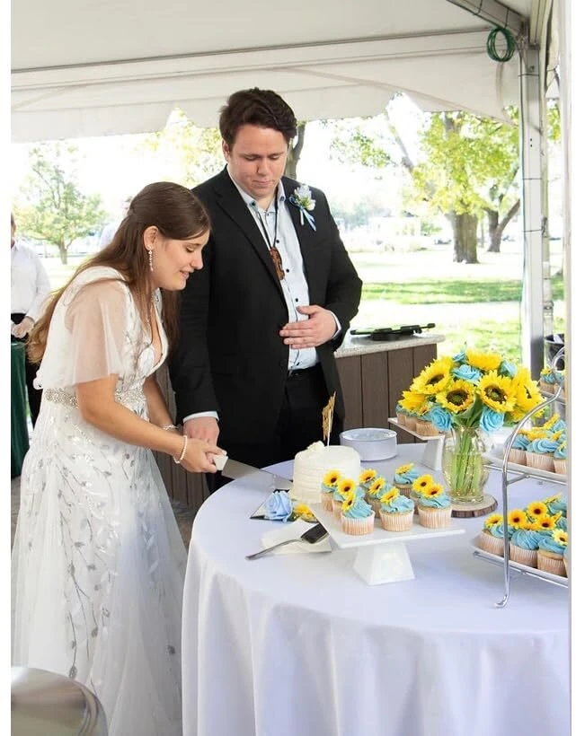 Wedding cake cutting under the reception tent in Lauren's embroidered gown