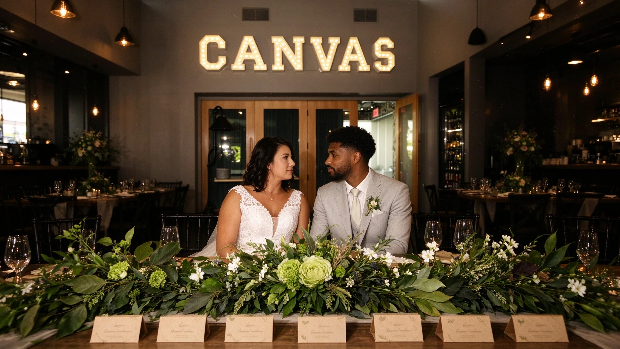 Couple seated together at the reception with the bride wearing a V-neck lace gown