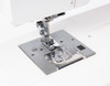 Janome Sewist 725S needle plate area with work light off, showing feed dog system and stitch width guide markings