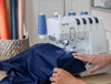 Hands guiding blue fabric through Brother Airflow 3000 serger in bright sewing room