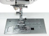Close-up of the Janome MC6650 needle plate area showing the one-push needle plate conversion system, seam guide markings, and top-loading rotary hook bobbin compartment