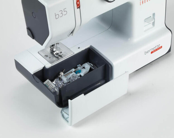 Bernette 35 sewing machine white accessory storage compartment with bobbins and presser feet shown open