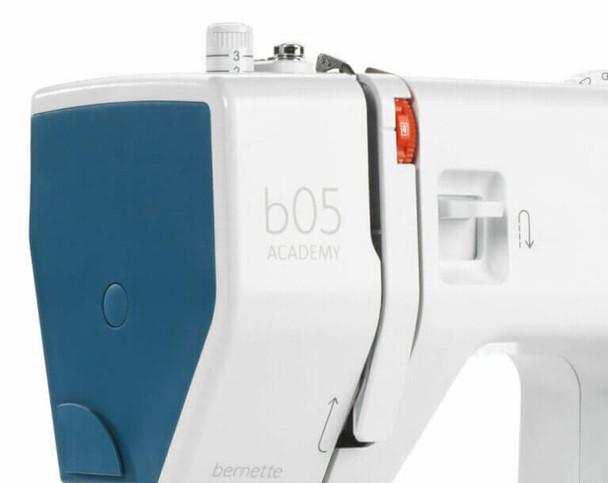 Bernette b05 Academy sewing machine close-up showing blue cover, carrying handle, and white body with tote bag