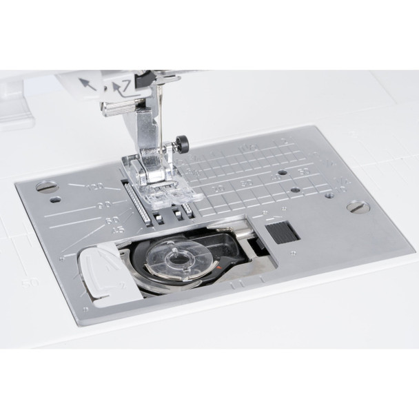 Close-up of the Janome Skyline S3 Anniversary Edition needle plate, showing stitch width markings and feed dog system