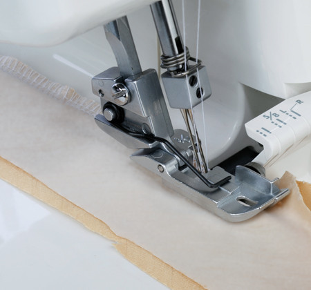 Janome serger laying in piping on a piece of fabric via serger